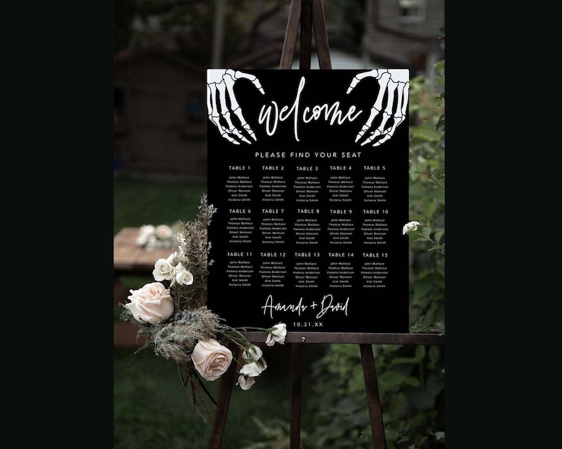 Puede incluir: Un cartel rectangular negro de distribuci&oacute;n de asientos para bodas con manos de esqueleto blancas en la parte superior, la palabra "welcome" en cursiva, el texto "PLEASE FIND YOUR SEAT", quince mesas con nombres y "Amanda + David" con "10.31.XX".