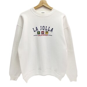 May include: White sweatshirt with a blue embroidered logo that says "LA JOLLA - CALIFORNIA" with colorful icons.