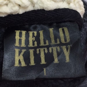 May include: Black fabric label with gold lettering that reads "HELLO KITTY".