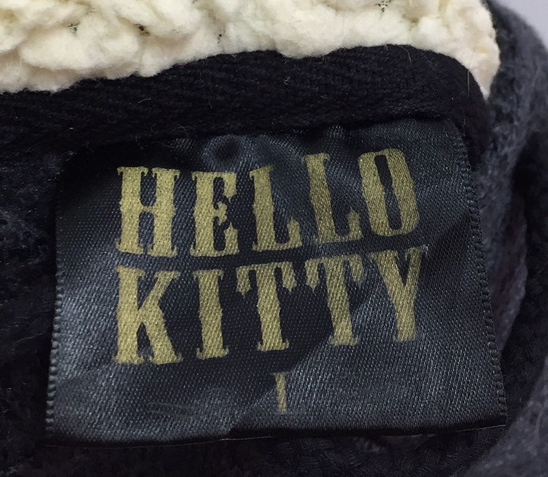 May include: Black fabric label with gold lettering that reads "HELLO KITTY".