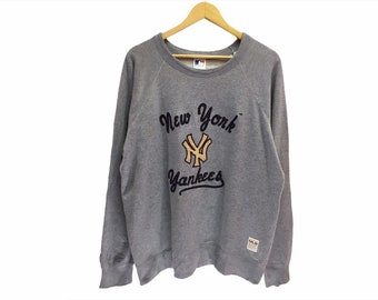 May include: Gray sweatshirt with a navy blue and gold New York Yankees logo and text. The logo features the iconic NY symbol.
