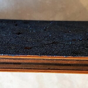 Puede incluir: Una caja de madera con una tapa de brillantina azul y un interruptor blanco en el lateral. La caja tiene un marco de madera oscura.