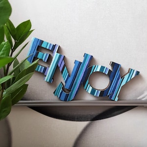 ENJOY. Allegra decorazione per la casa. Cartone decorato a strisce multicolori. Appendere al muro o appoggiare su un mobile. Leggerissima