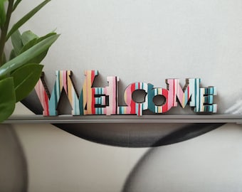 WELCOME. Allegra decorazione per la casa. Cartone decorato a strisce multicolori. Appendere al muro o appoggiare su un mobile. Leggerissima