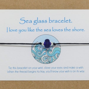 May include: A sea glass bracelet with a blue glass bead and black string. The card reads "Sea glass bracelet. I love you like the sea loves the shore. Tie this bracelet on your wrist, close your eyes and make a wish. When the thread begins to fray, you'll know your wish is on its way."