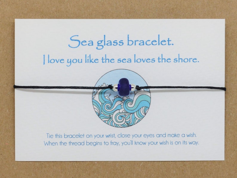May include: A sea glass bracelet with a blue glass bead and black string. The card reads "Sea glass bracelet. I love you like the sea loves the shore. Tie this bracelet on your wrist, close your eyes and make a wish. When the thread begins to fray, you'll know your wish is on its way."