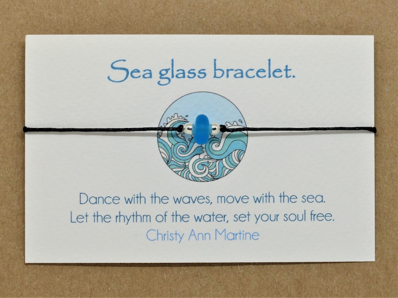 May include: A sea glass bracelet with a blue sea glass bead on a black cord. The card reads "Sea glass bracelet. Dance with the waves, move with the sea. Let the rhythm of the water, set your soul free. Christy Ann Martine."