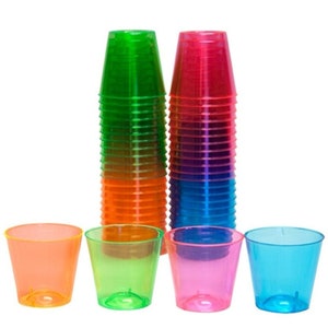 Puede incluir: Un conjunto de 25 vasos de chupito de plástico de color neón verde, naranja, rosa y azul. Los vasos son transparentes y tienen un ligero brillo iridiscente.