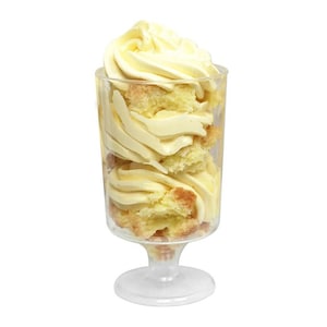 Op de afbeelding: Een heldere glazen dessertbeker met een voet, gevuld met lagen van vanillecake en slagroom.