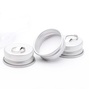 May include: Three silver bottle caps with a small ring attached to the top of each cap.