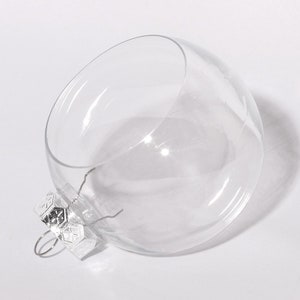 May include: A clear glass ornament with a silver metal top. The ornament is round and has a smooth surface.
