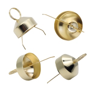 Może przedstawiać: Cztery złote metalowe świeczniki z uchwytem w kształcie pierścienia i trzema małymi nóżkami. Świeczniki mają okrągłą podstawę i stożkową górę. Obraz jest na białym tle.