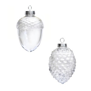 May include: Two clear glass Christmas ornaments shaped like acorns. The ornaments have a silver cap and are ready to be hung on a Christmas tree.