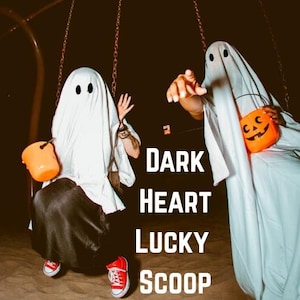 May include: Two people dressed as ghosts, wearing white sheets with eye holes, are on a swing set. One holds an orange bucket, the other an orange jack-o'-lantern candy bag. The text "DARK HEART LUCKY SCOOP" is in the image.