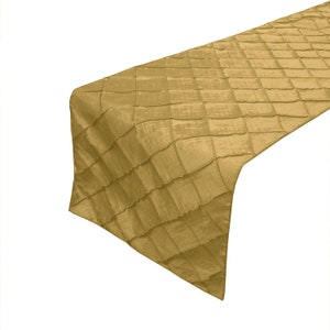 May include: A gold table runner with a quilted diamond pattern. The runner is made of a soft, luxurious fabric and is perfect for adding a touch of elegance to any table setting.