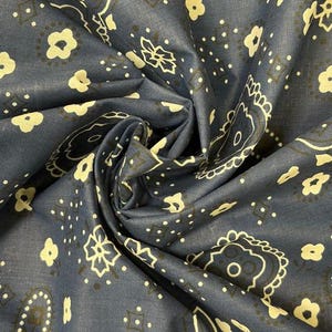 May include: A dark blue fabric featuring a repeating pattern of cream-colored floral motifs, paisley shapes, and small geometric dots. The textile is gathered in the center, creating folds that highlight the intricate, symmetrical print design.