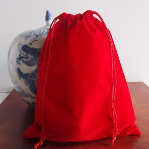 May include: A red velvet drawstring bag with a white cord.