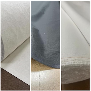 May include: Three rolls of fabric, one white, one gray, and one white with a red stitching detail. The fabric is smooth and appears to be a woven material.