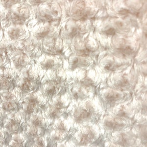May include: White fluffy fabric with a textured, swirl pattern. The fabric has a soft, plush feel.
