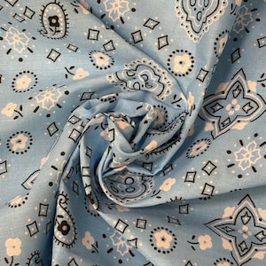 May include: A light blue fabric featuring a repeating bandana pattern in white and black. The design includes small floral motifs, geometric diamond shapes, and intricate paisley-inspired swirls arranged across the surface of the material.
