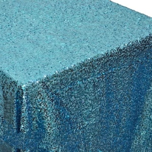 May include: A teal blue sequin tablecloth. The tablecloth is made of a soft, shimmery fabric with a subtle sheen.