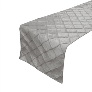May include: A silver table runner with a diamond pattern. The runner is made of a soft, textured fabric.