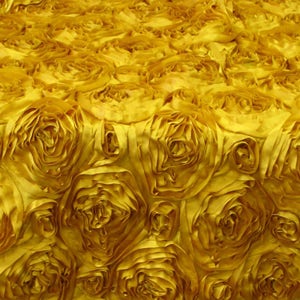 May include: A yellow fabric tablecloth with a rosette design. The fabric is made of satin and has a soft, luxurious feel.
