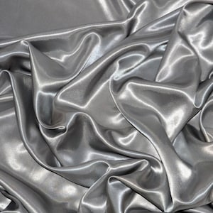 May include: A close-up of a silver satin fabric, showing its smooth, silky texture and the way it drapes and folds.