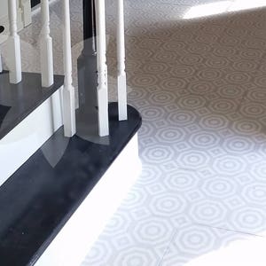 Könnte beinhalten: Ein schwarz-weißer Musterboden mit einer weißen Treppe mit schwarzen Stufen und einem weißen Geländer. Das Geländer hat weiße Spindeln und einen schwarzen Pfosten.