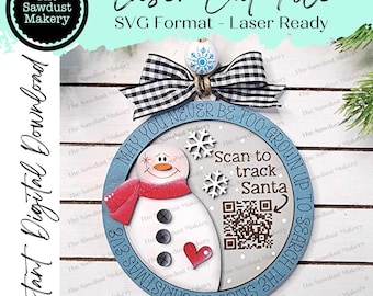 May include: A blue and white round wooden ornament with a snowman and a QR code. The ornament reads "May you never be too grown up to search the skies on Christmas Eve" and "Scan to track Santa".