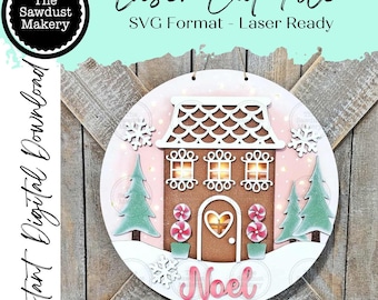 Könnte beinhalten: Runde, lasergeschnittene Weihnachtsdekoration mit Lebkuchenhaus-Design. Das Haus ist braun mit weißen Akzenten, umgeben von grünen Bäumen, Schneeflocken und dem Wort "Noel". Der Text "Laser Cut File" und "Instant Digital Download" ist ebenfalls sichtbar.