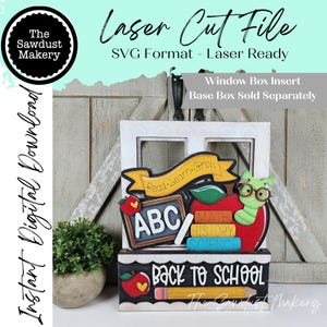 May include: A laser cut file digital download featuring a window box insert with a school theme. The design includes a yellow banner reading Read Learn Grow, a chalkboard with ABC, a red apple, a green worm with glasses, and books labeled Math, History, Science. The base box insert reads Back to School with a pencil graphic.