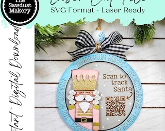 May include: A blue and pink wooden nutcracker ornament with a gold crown and a QR code that says "Scan to track Santa". The ornament is decorated with the text "Sugar Plum Fairies ~ The Nutcracker ~ The Mouse King ~ Soldiers ~ The Toy of the Soldiers".