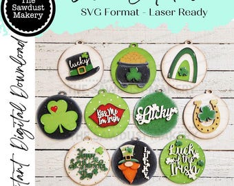 May include: Ten round laser cut wood ornaments with a St. Patrick's Day theme. The ornaments feature shamrocks, leprechauns, pots of gold, horseshoes, rainbows, and the words "Lucky", "Kiss Me I'm Irish", and "Luck of the Irish".