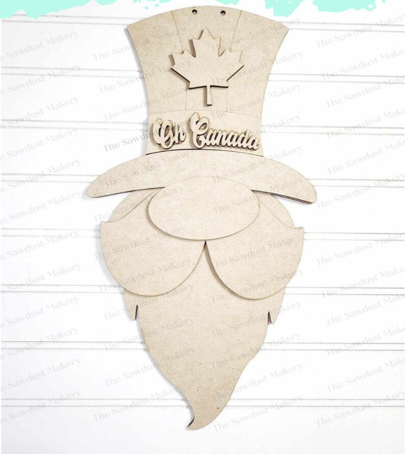 May include: A wooden cutout of a Canadian gnome wearing a top hat with a maple leaf on top. The hat has the words "Oh Canada" written on it. The gnome has a long beard.