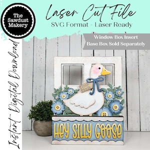 May include: A laser-cut wooden window box insert featuring a white goose with a pink cheek and yellow beak, adorned with blue flowers and the text "Hey Silly Goose." The design includes the text "Laser Cut File" and "SVG Format - Laser Ready."