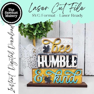 May include: A wooden decorative sign with the words "Bee", "Humble", and "& kind" in a stacked arrangement. The sign has a yellow and blue color scheme with a dark brown base. The text "Laser Cut File" is also visible.