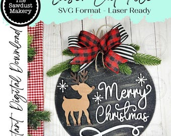 May include: A circular black wooden Christmas decoration featuring a reindeer and the words "Merry Christmas" in white. It's adorned with a red and black checked bow, greenery, and snowflakes. The text "Laser Cut File" is visible at the top.