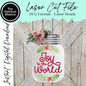 May include: A mason jar-shaped laser cut file with the text "Joy to the World" in red script. The jar is decorated with green sprigs, red berries, and a striped bow. The words "Laser Cut File" and "SVG Format - Laser Ready" are also visible.