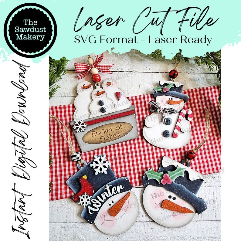 May include: Four laser cut wooden snowman ornaments with different designs. The ornaments are painted white, black, red, and blue. One snowman has a bucket of flakes sign, another has a winter sign, and the other two have holly and a candy cane.