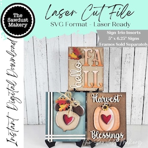 May include: A digital laser cut file set featuring three rectangular sign inserts measuring 12.7 cm by 15.88 cm. The designs include a hello FALL sign, an acorn with leaves and a heart, and a pumpkin with the text Harvest Blessings.