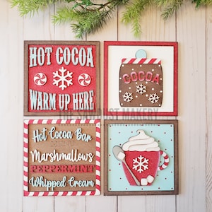 May include: Four wooden signs with a winter holiday theme. The signs feature red and white candy canes, snowflakes, and a cocoa mug with whipped cream. The text on the signs reads "Hot Cocoa Warm Up Here", "Hot Cocoa Bar Menu Marshmallows Peppermint Whipped Cream", and "Cocoa".
