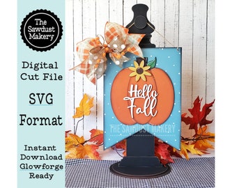 May include: A wooden sign with a blue background and white polka dots features a large orange pumpkin with a sunflower on top. The pumpkin has the words "Hello Fall" written on it. The sign is attached to a black wooden stand.