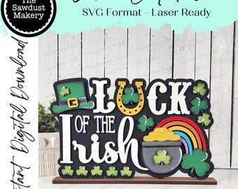 May include: A laser cut file for a wooden sign that says "Luck of the Irish" with a shamrock, horseshoe, pot of gold, and rainbow. The sign is on a brown wooden base.