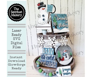 May include: A tiered tray decorated with winter-themed wooden signs. The signs feature a snowman, a Christmas tree, and the phrases "Hello Winter", "Baby It's Cold Outside", "Friends Are Snowflakes", and "Frozen Yogurt".