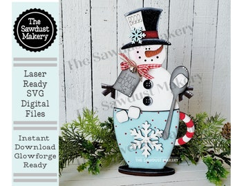 Könnte beinhalten: Ein hölzerner Schneemann, der eine blaue und weiße Tasse mit einem roten und weißen Zuckerstangen-Griff hält. Der Schneemann trägt einen schwarzen Zylinder mit einem roten Band und einem weißen Schneeflocke. Die Tasse hat ein Schneeflocken-Design und den Text "HOT COCOA 5¢".