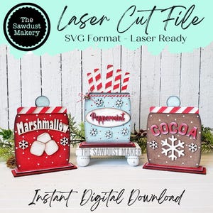 Peut inclure: Trois décorations de Noël en bois, chacune avec un thème différent : "Marshmallow", "Menthe poivrée" et "Cacao". Chaque décoration présente un dessus rayé rouge et blanc, une base avec des flocons de neige et un design unique. La décoration "Marshmallow" a deux guimauves blanches, la décoration "Menthe poivrée" a des cannes en sucre rayées rouge et blanc, et la décoration "Cacao" a un grand flocon de neige.