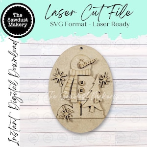 May include: A laser cut file in SVG format featuring an oval wooden ornament design. The ornament displays a snowman with a carrot nose, a scarf, and two buttons, accompanied by a pine tree and three snowflakes. Text includes The Sawdust Makery.