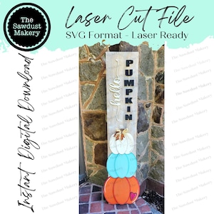 May include: A wooden sign with the words "hello pumpkin" and a stack of three pumpkins in orange, teal, and white. The pumpkins are decorated with a stem and a leaf.