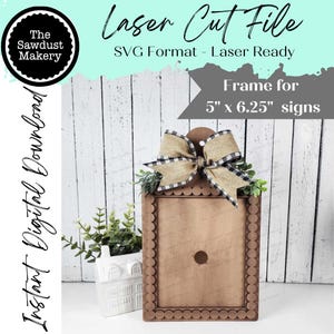 May include: A laser cut file for a 5 inch by 6.25 inch sign frame. The frame is made of wood and has a decorative border with a bow at the top. The frame is ready to be used for a sign.